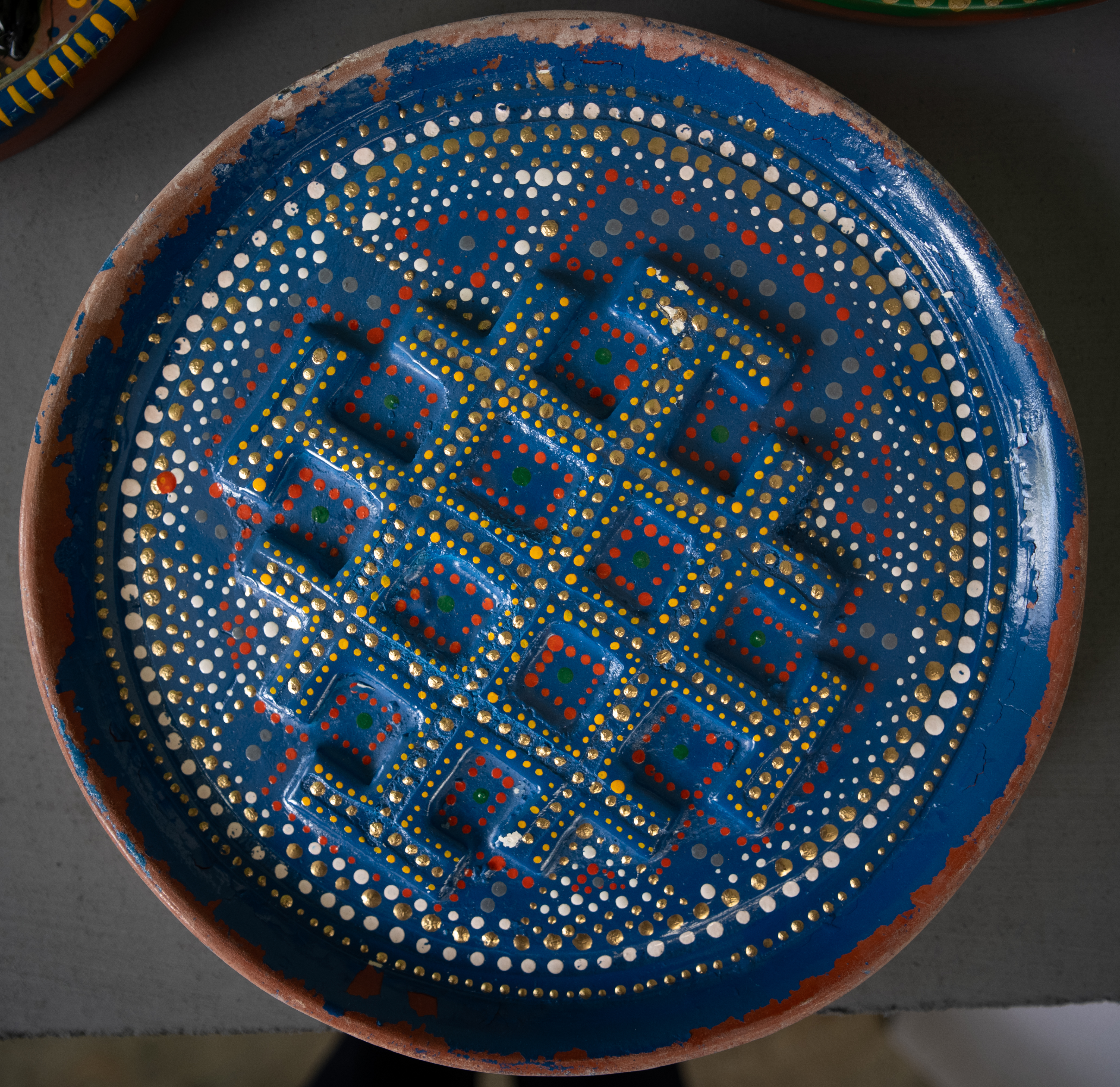 Round blue object covered with interlocking raised forms and dotted patterns